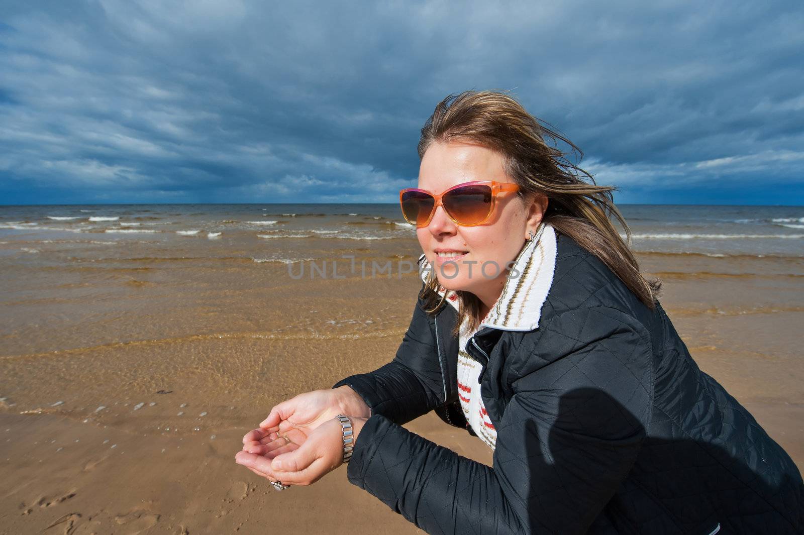 Portrait of mature attractive woman in sunglasses relaxing at the Baltic sea in autumn day.