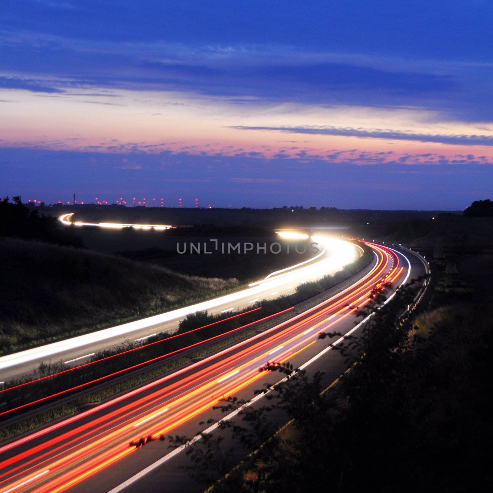 night traffic on busy highway with cars lights and blue sky