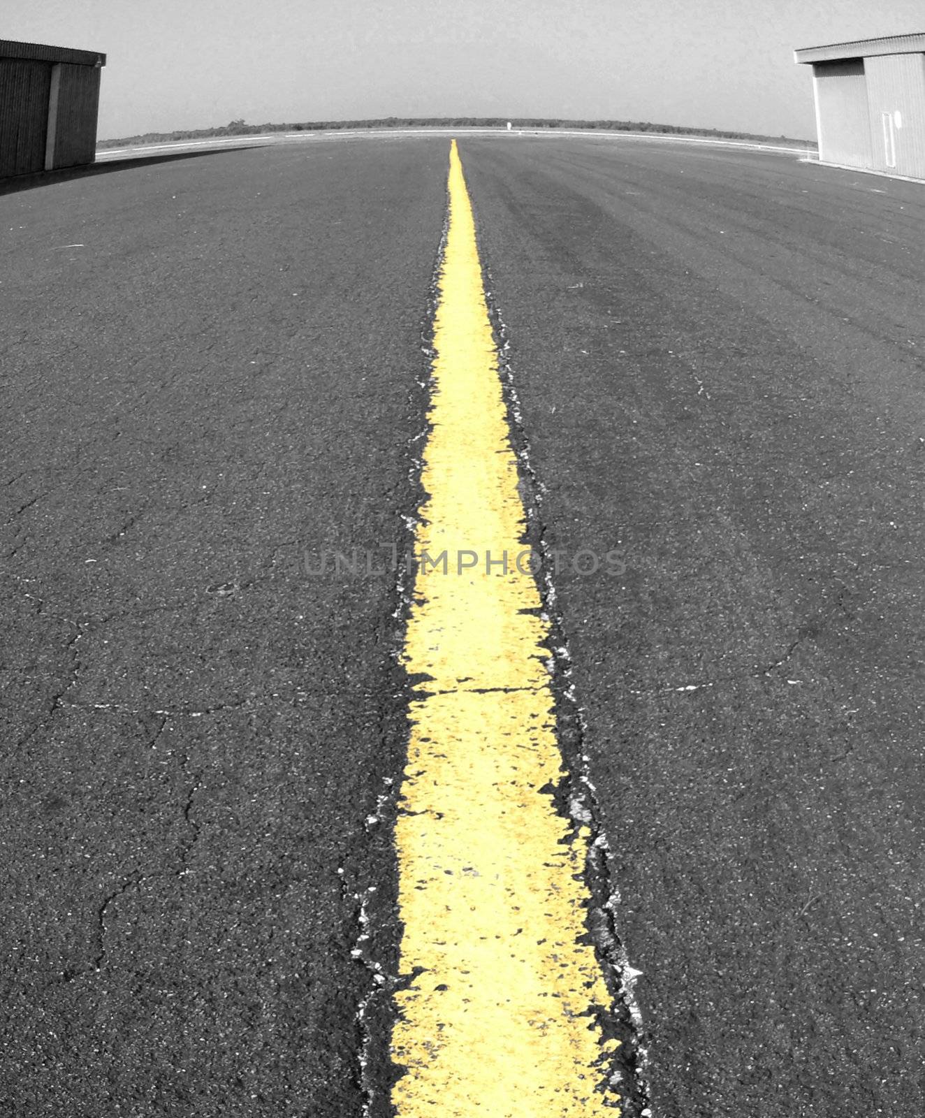 Black and white with single yellow punch on centerline of airport taxiway with fisheye distortion