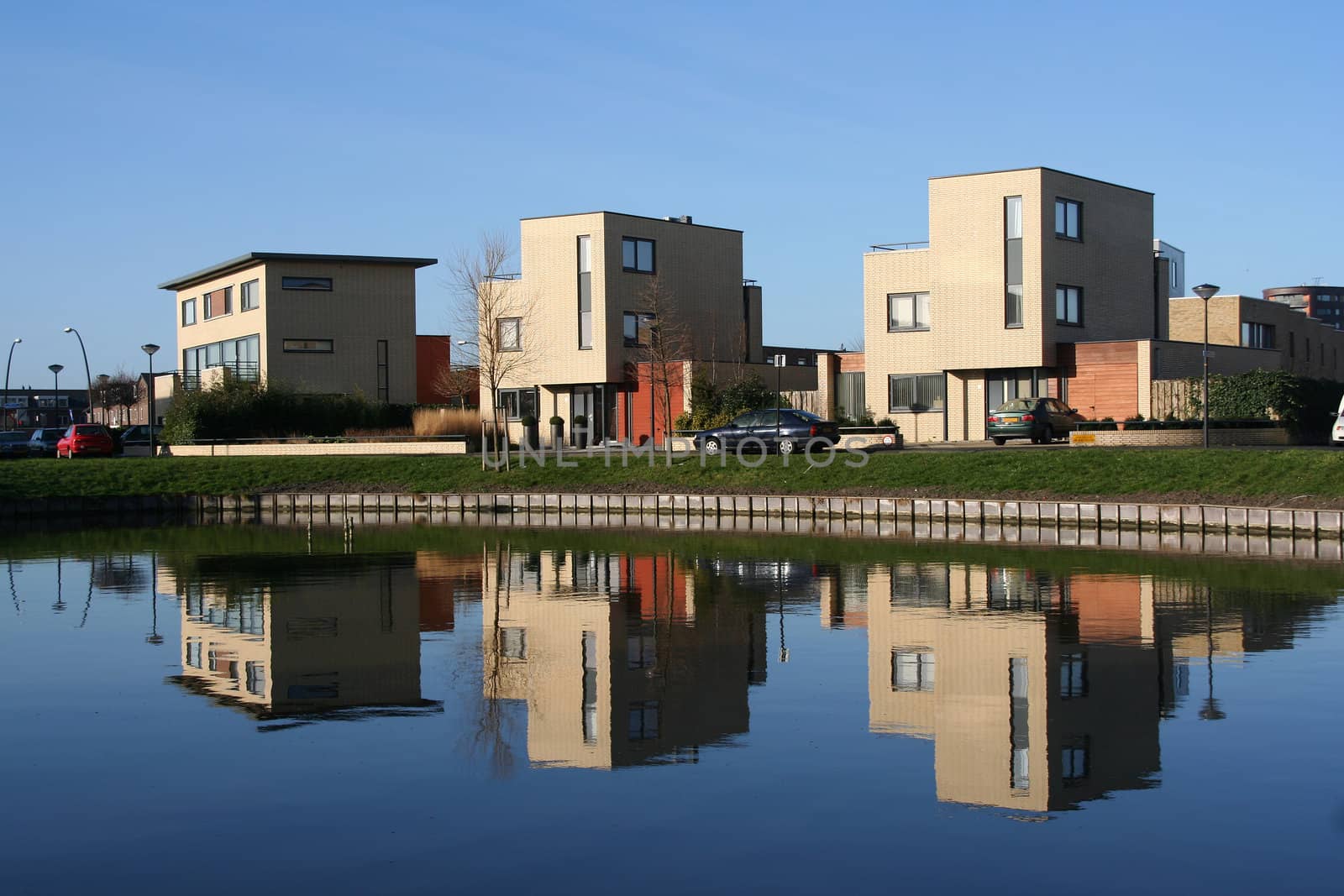 Three houses and their reflection in a pond in a modern suburb