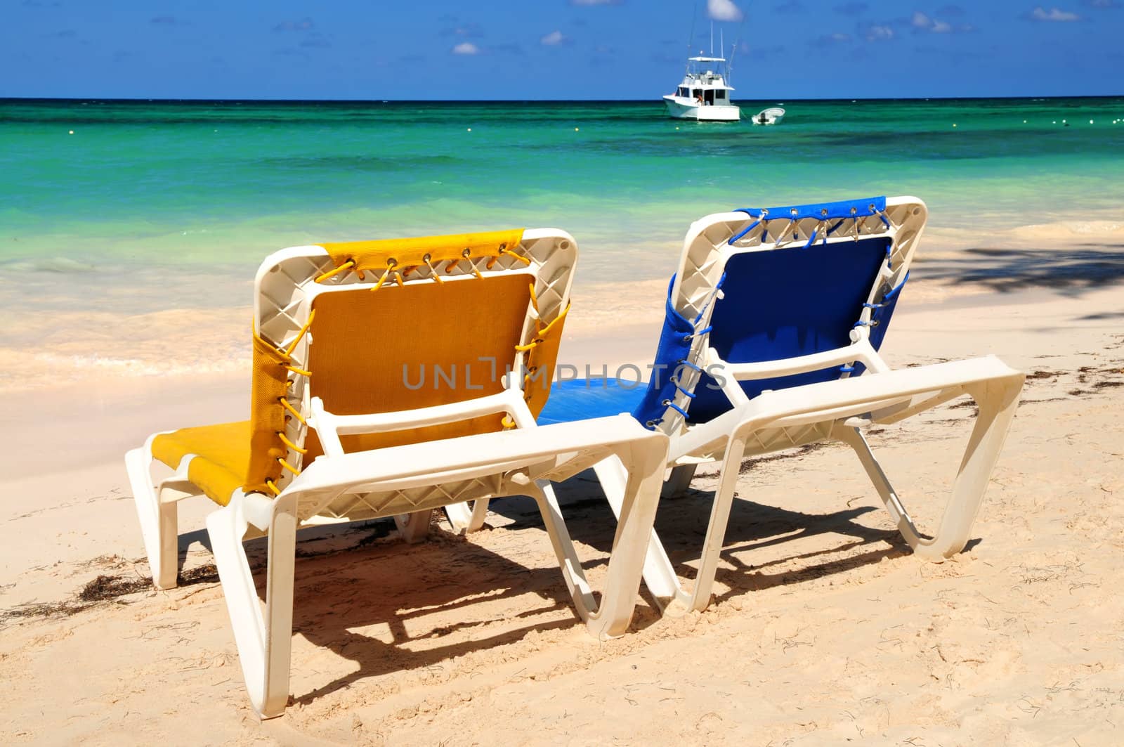 Chairs on sandy tropical beach by elenathewise