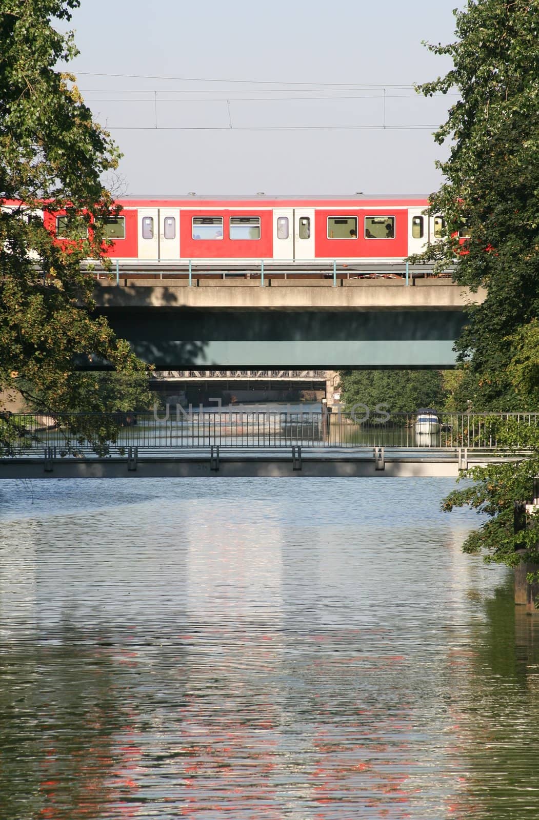 Commuter train on a bridge over a canal near the city center of Hamburg, Germany. Also: a narrow pedestrians' bridge in the foreground. Hamburg has 2500 bridges ;-)