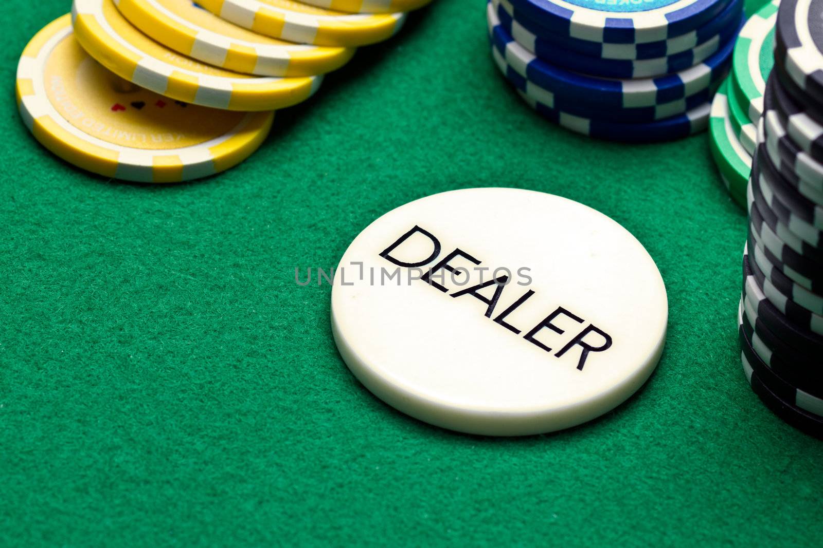 Poker dealer button and chips on green felt