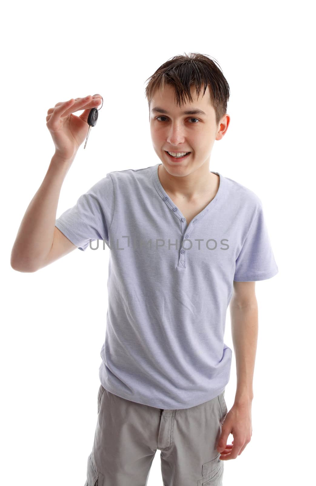 A male teenager holding a car key in one hand. White background.l