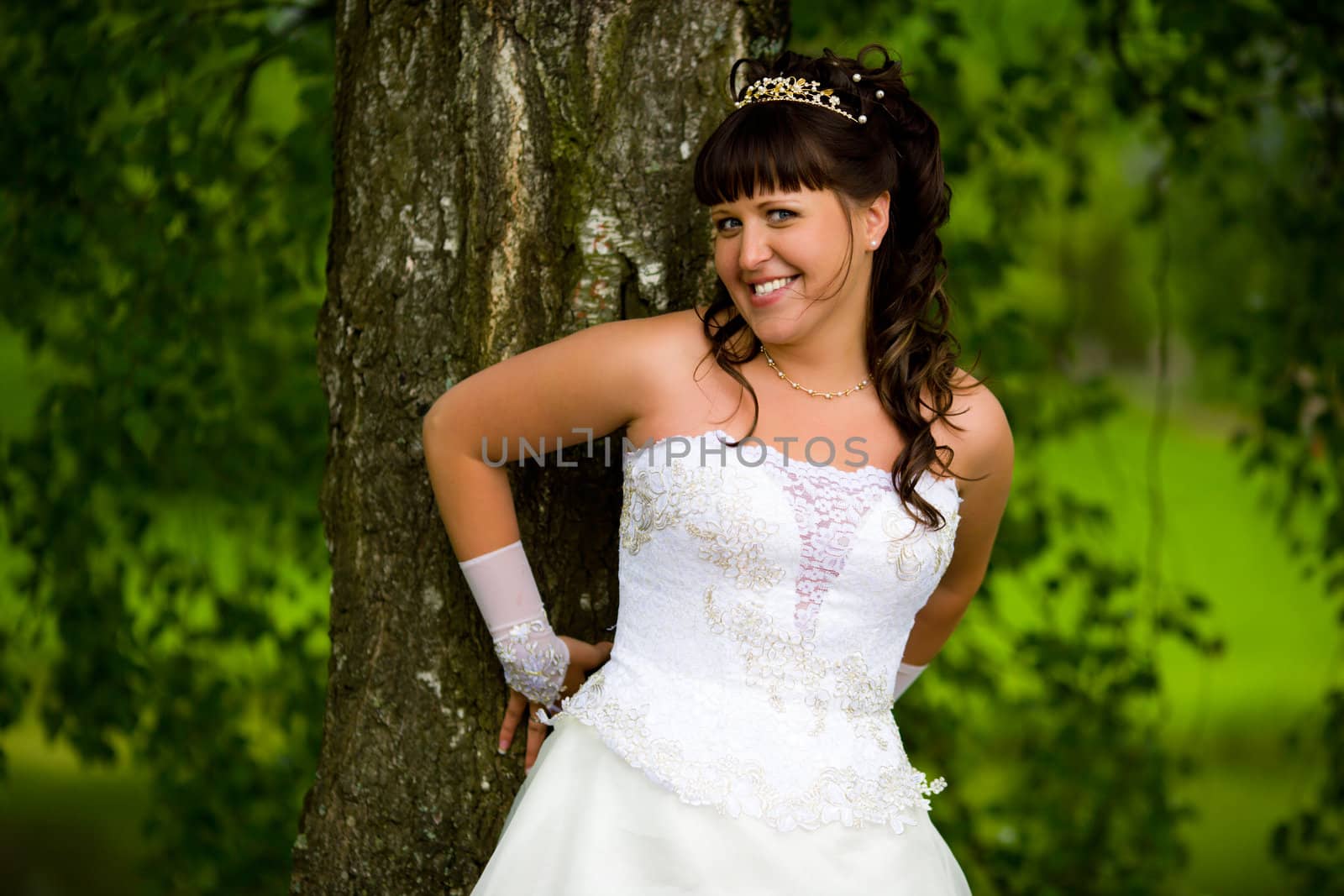 Happy Bride smiling near summer tree outdoors 