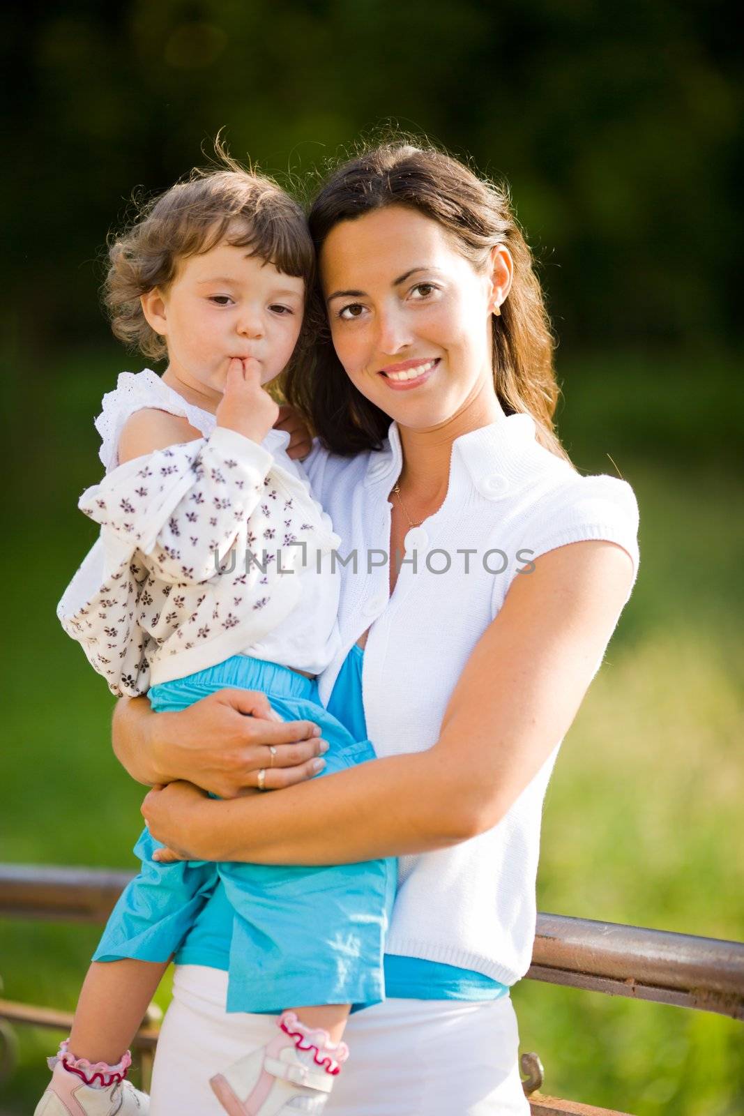 Happy mother holding one year daughter summer outdoors