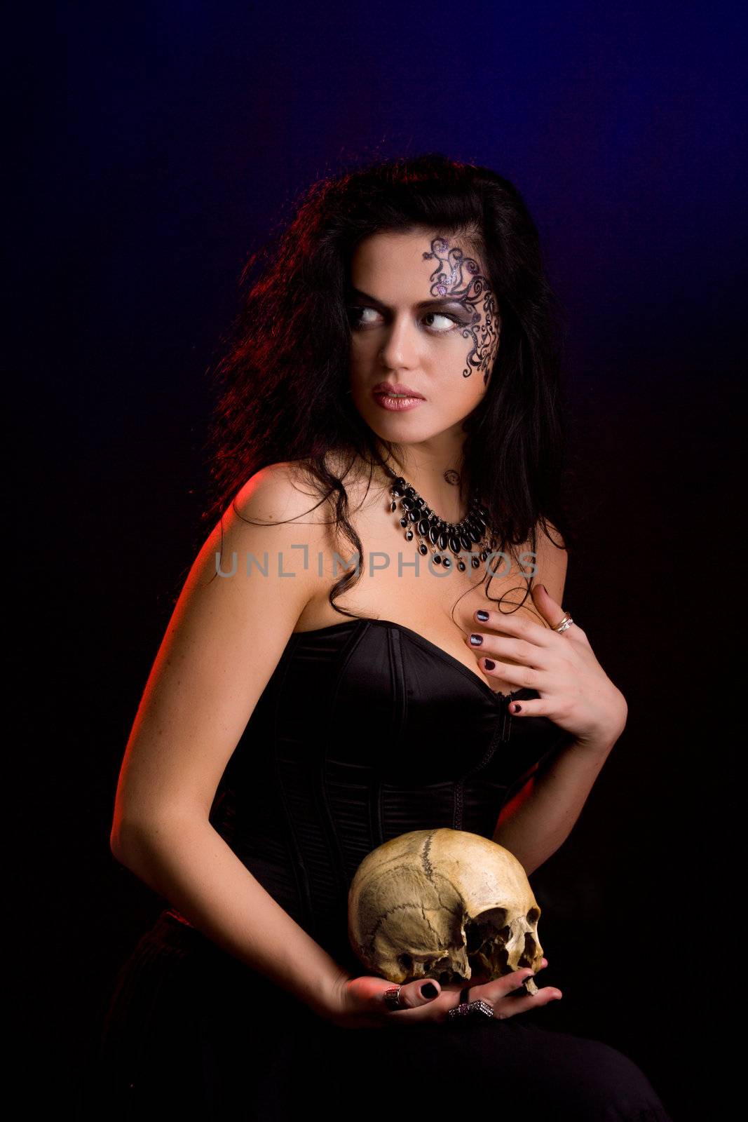 Young beautiful demonic female creature holding scull