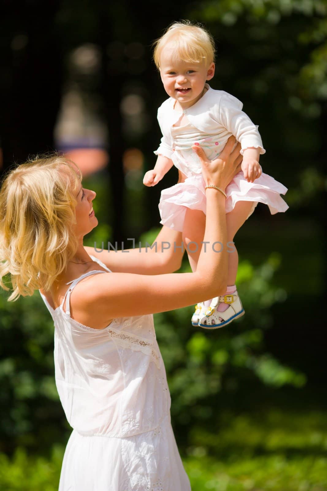 Happy mother playing with one year daughter outdoors