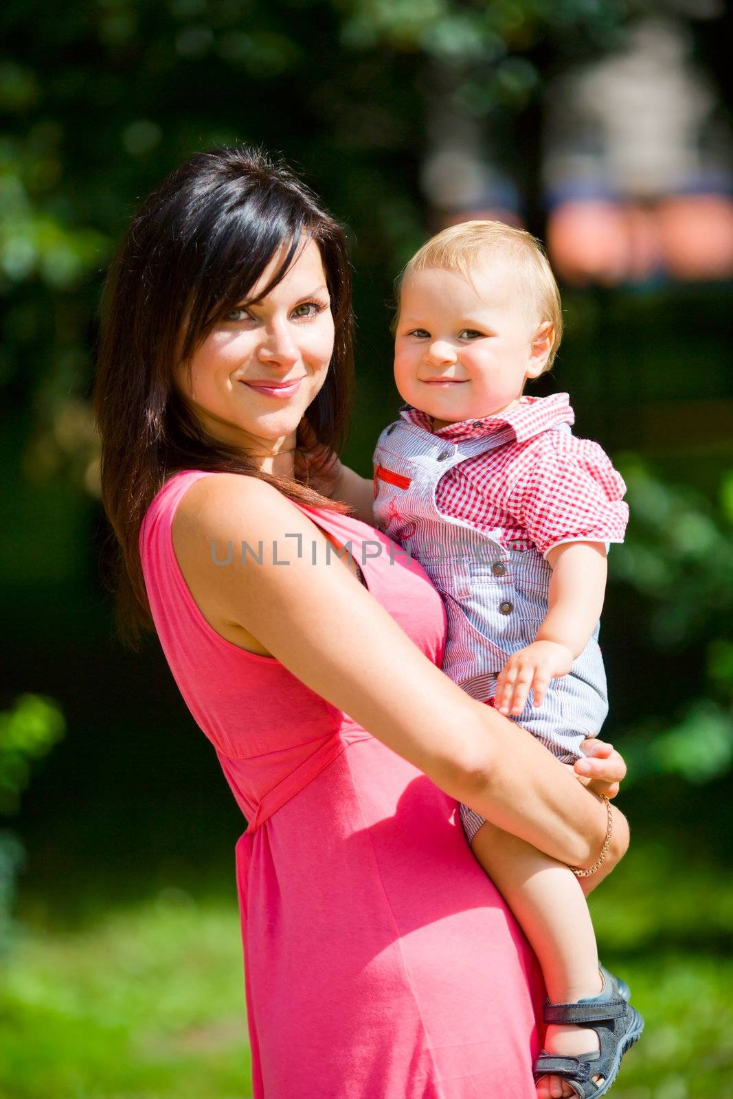 Happy mother holding one year son summer outdoors