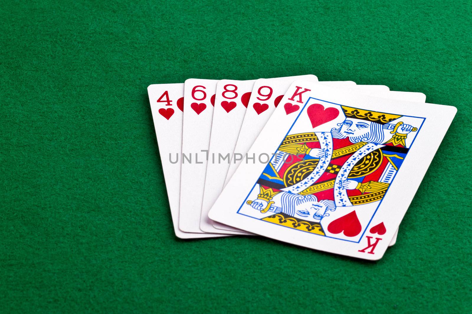 Poker hand with a flush of hearts on green felt
