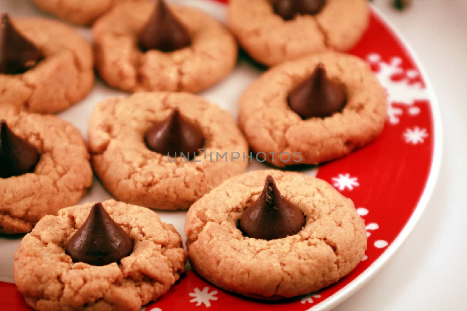 Tasty peanut butter cookies with chocolate kisses for the holidays. Christmas dessert on a red and white snowflake dinner plate. Holiday treats for the season.