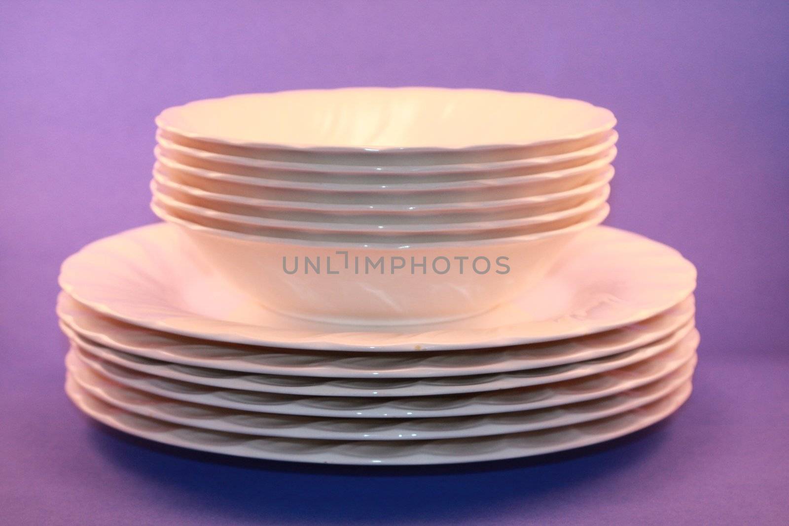 White dinner plates stacked in a pile with a blue background. White dinnerwear for meals, holidays and special occasions.