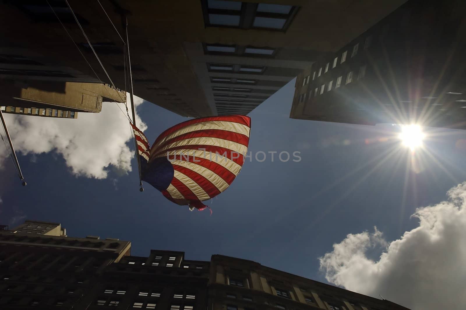 waving usa flag in the middle of urban architecture, photo taken against sun