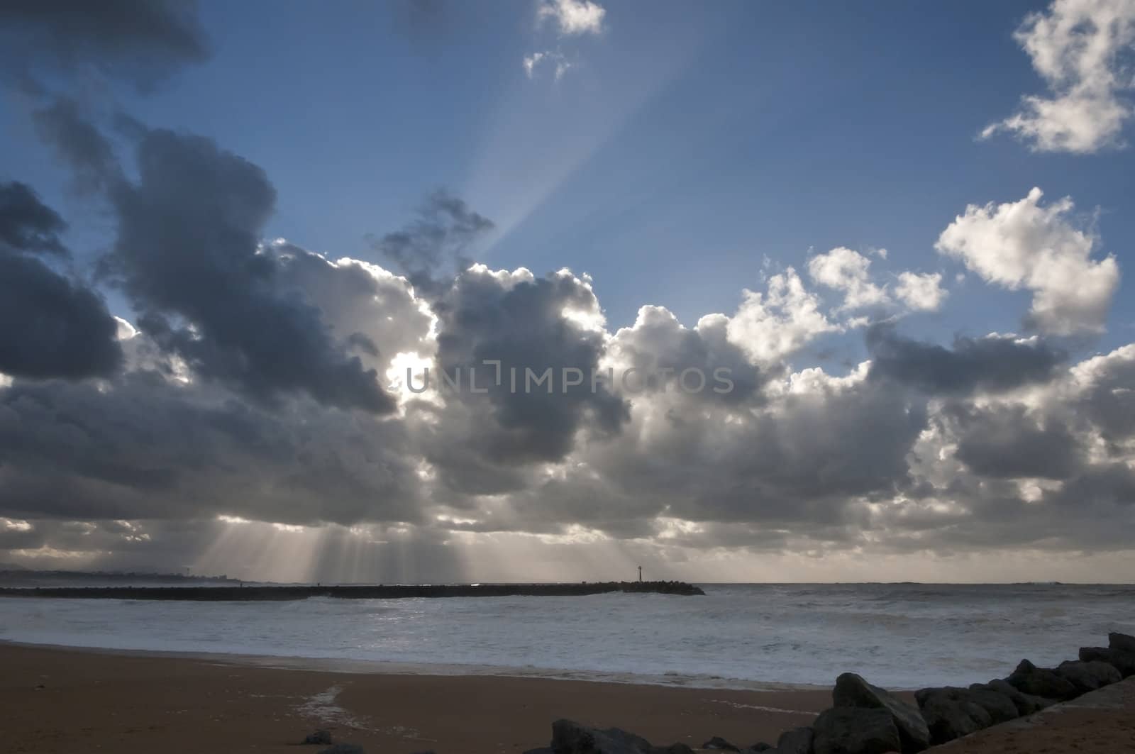 Many sunlight rays through big clouds above the sea during a stormy day