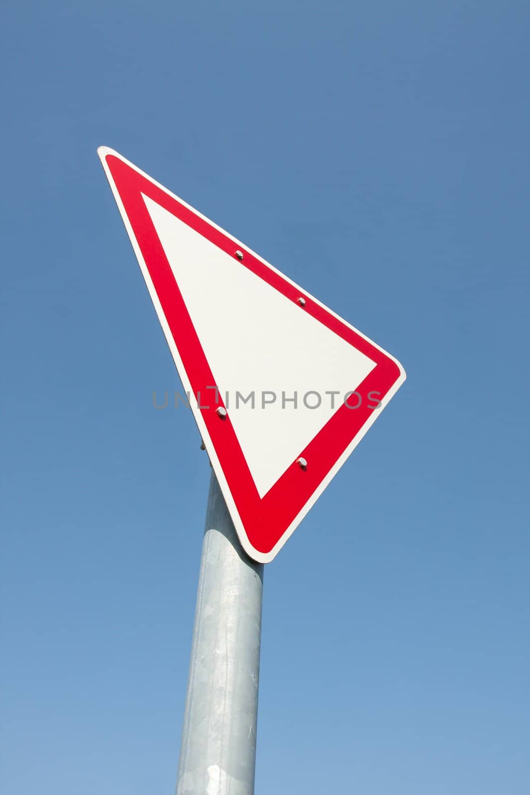 Yield traffic sign against clear blue sky