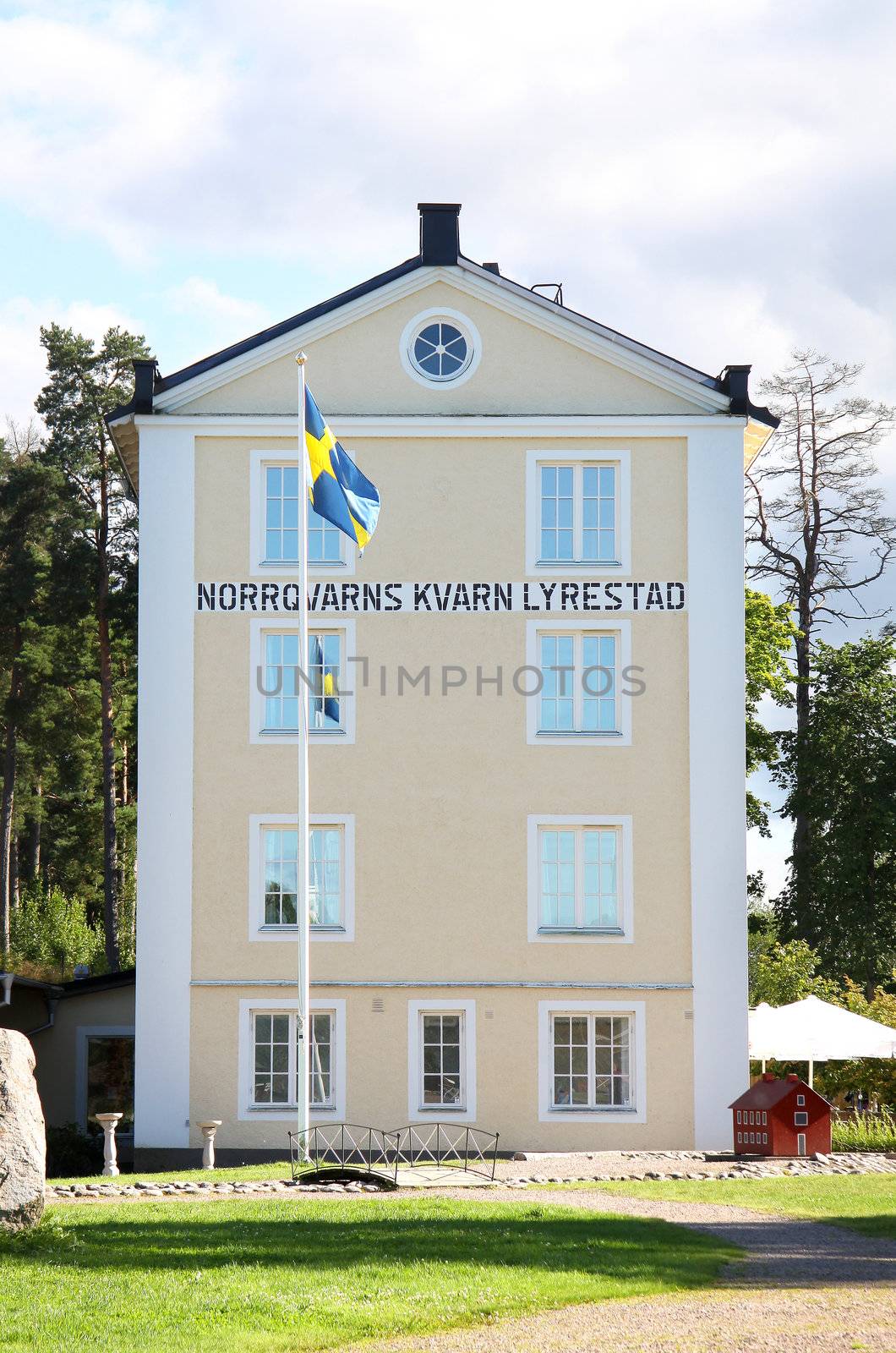 A hotel in Sweden, with green lawn and swedish flag in front of it
