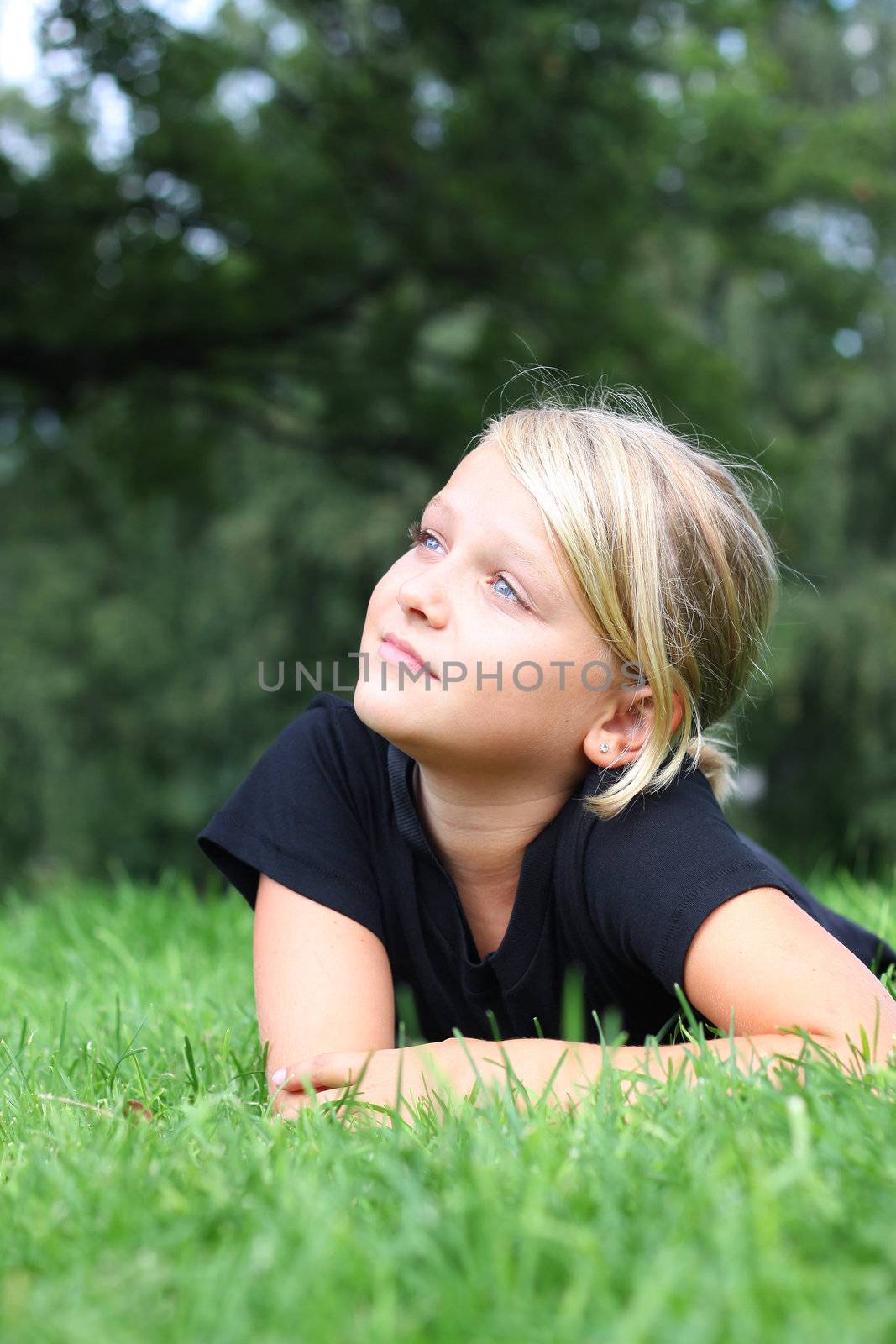 Child looking up at the sky in a green park