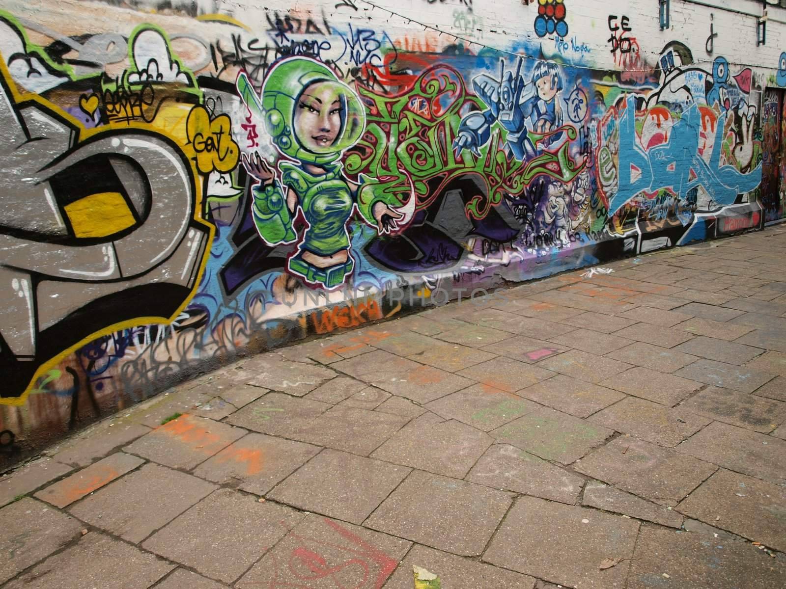A perspective of a street with graffitti painted wall and fragment of a pavement