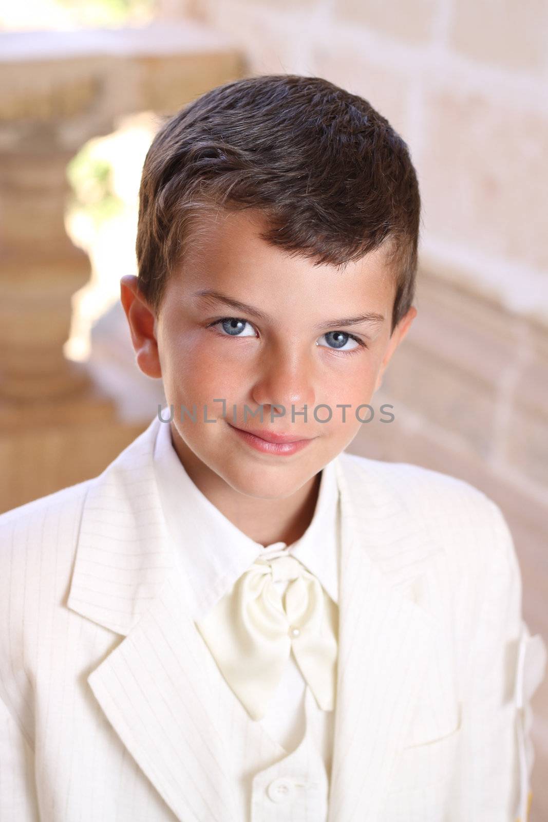 Portrait of boy doing his holy communion dressed in white wedding suite jacket