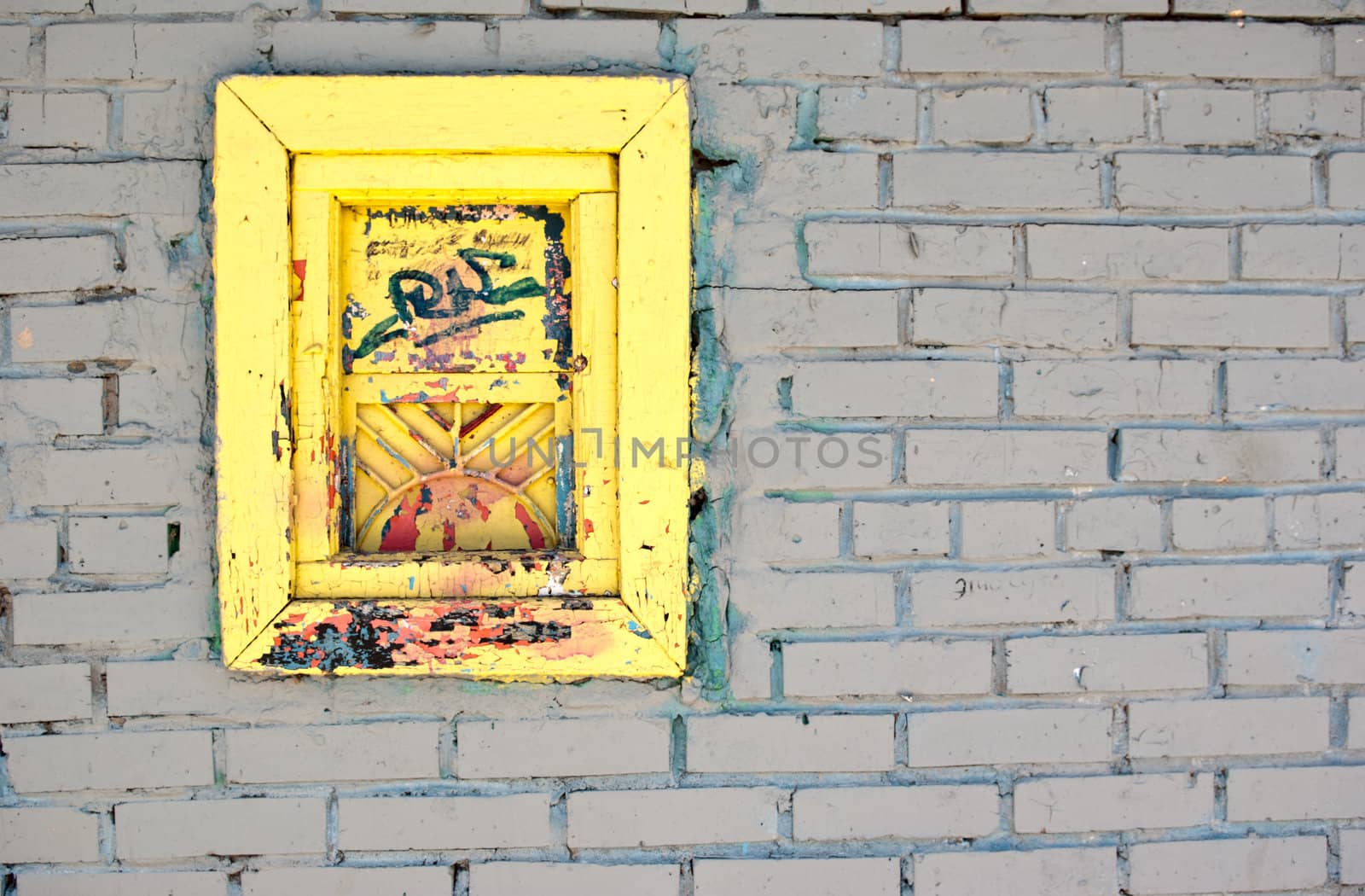 White brick wall with a yellow old window