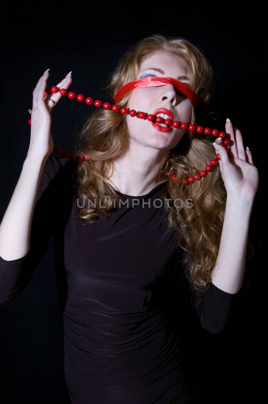 Woman with bandage on her eyes bites red necklace