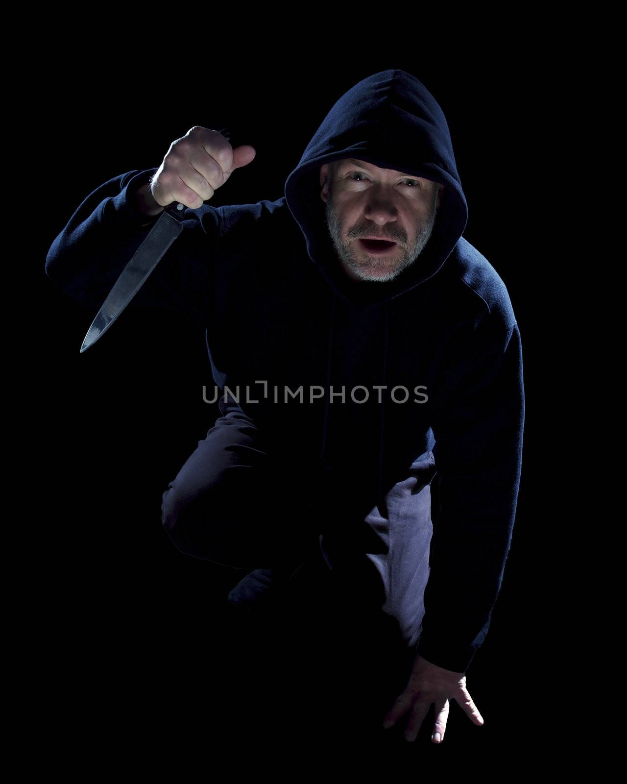 Crouching burglar with kitchen knife on black