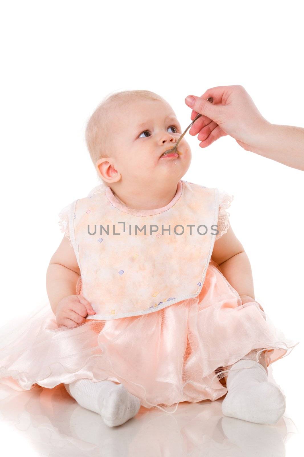 Baby eating from spoon in mother's hand isolated on white
