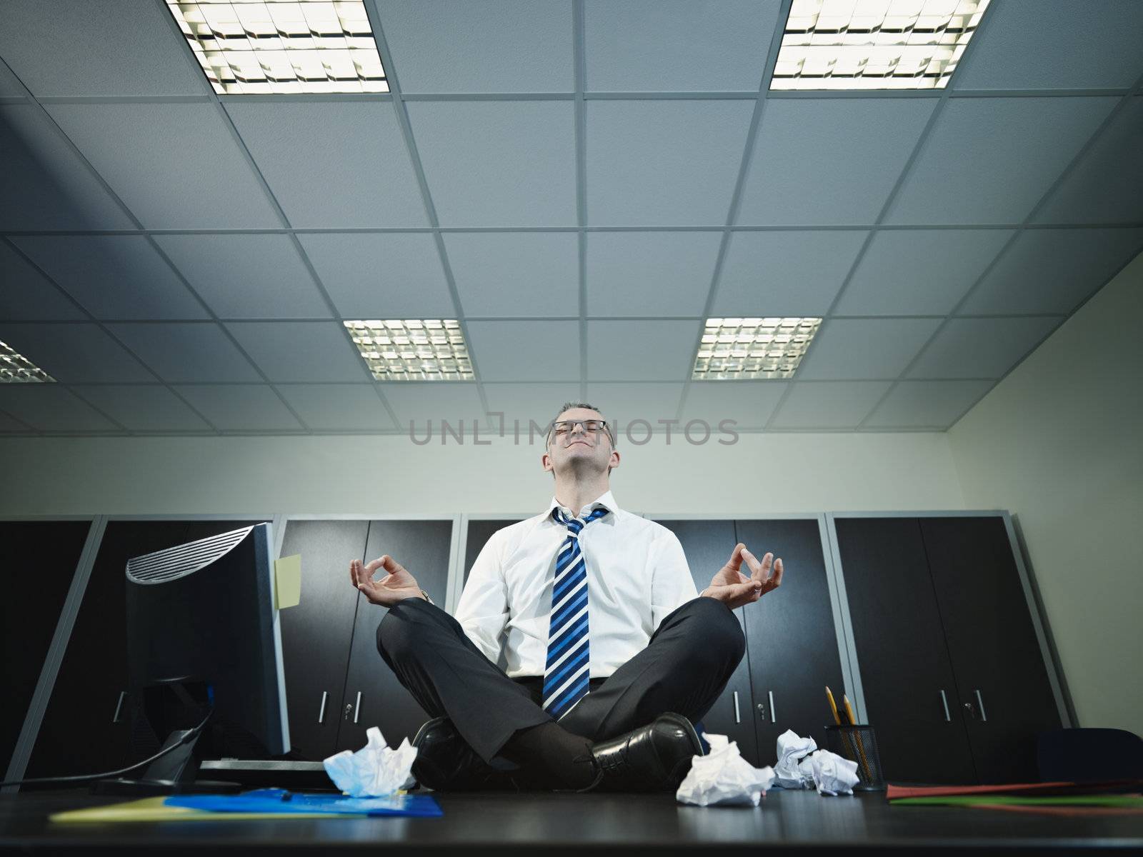 businessman doing yoga in office by diego_cervo