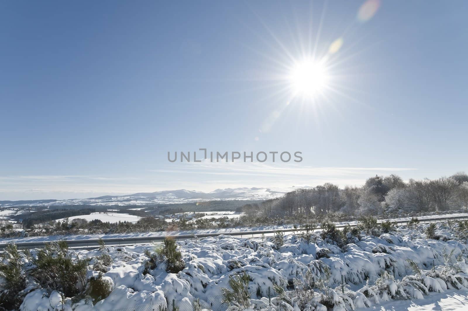 Winter landscape with a blue sky and lot of snow and also with a motorway