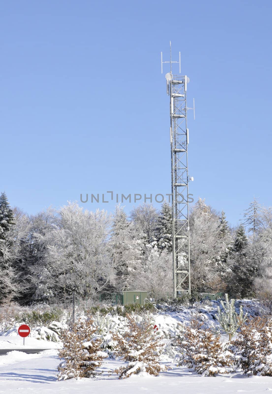 Winter landscape with antennas in trees on a blue sky with snow