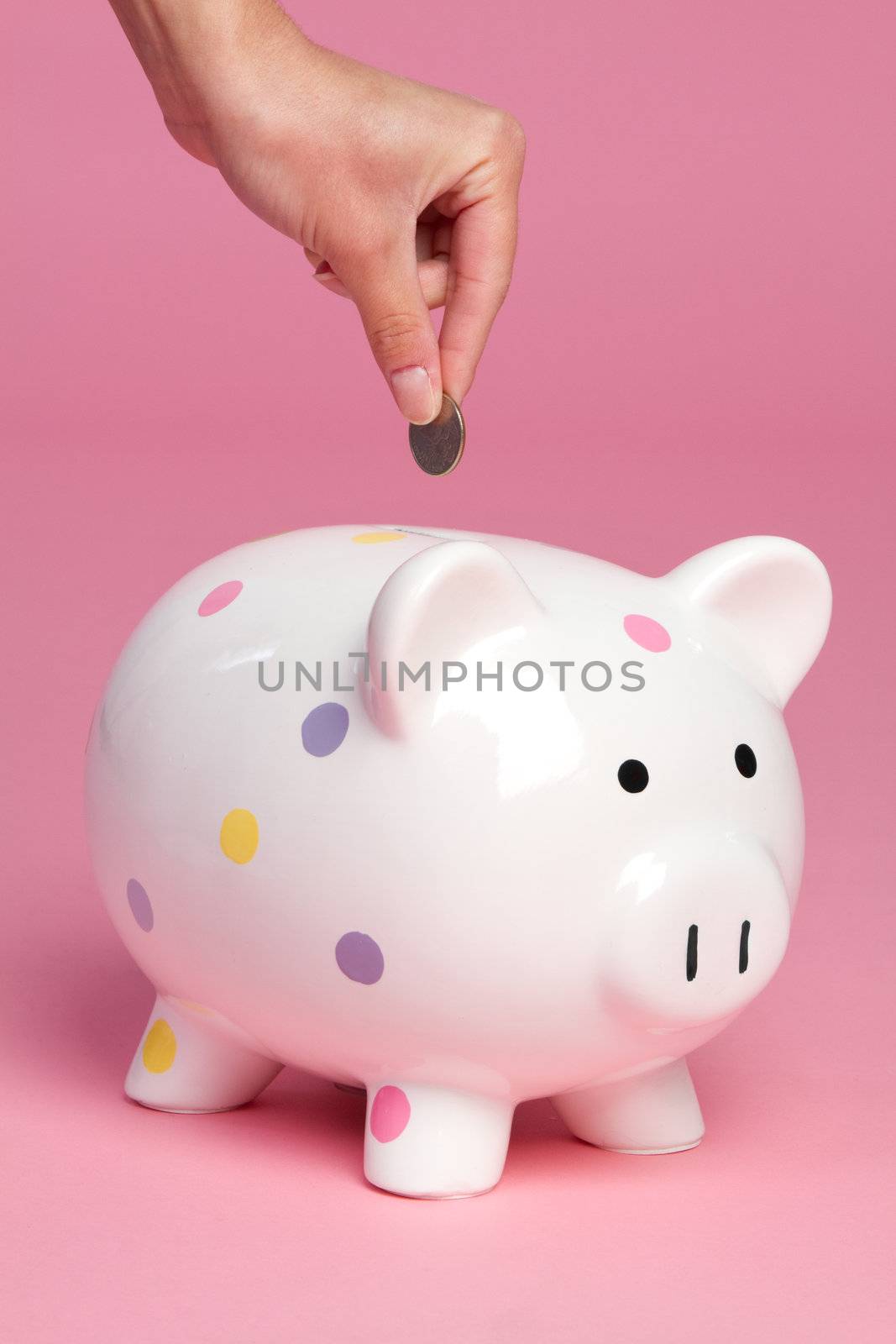 Person dropping coin into piggy bank