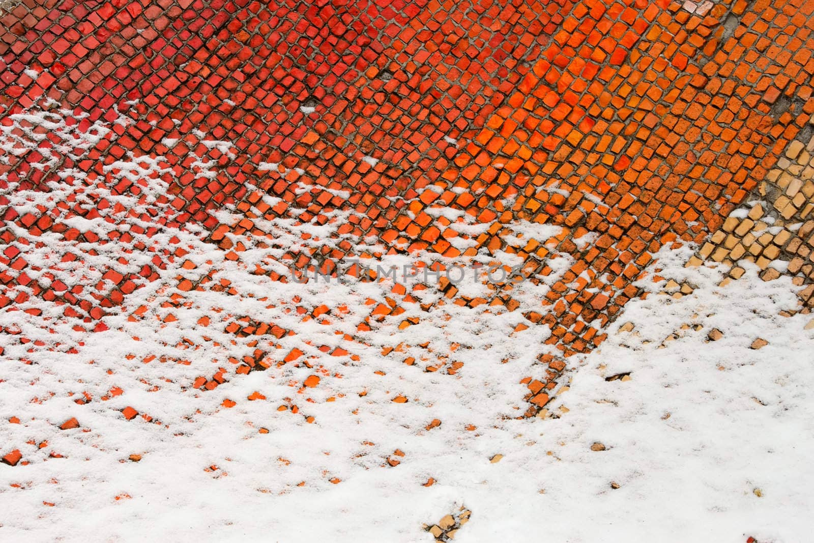 A fragment of an old colored mosaics partially covered with snow. Beginning of winter 