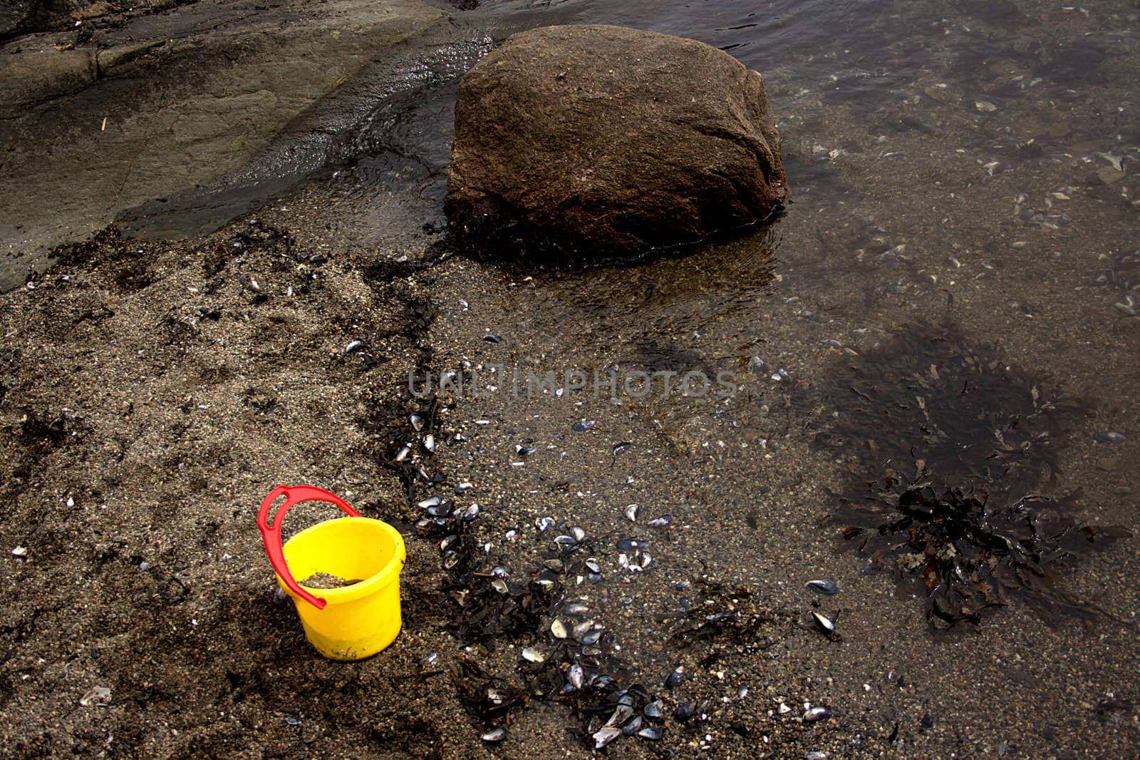 Lonely yellow plastic bucket on sandy beach