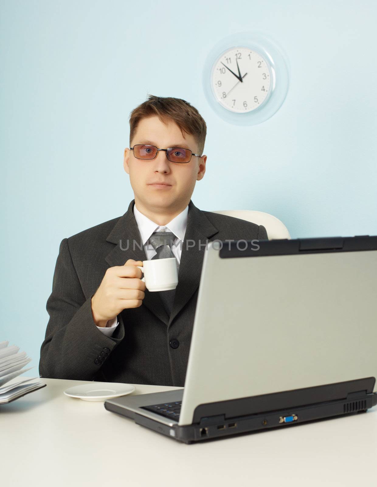 The serious man at office with the laptop and a cup of coffee