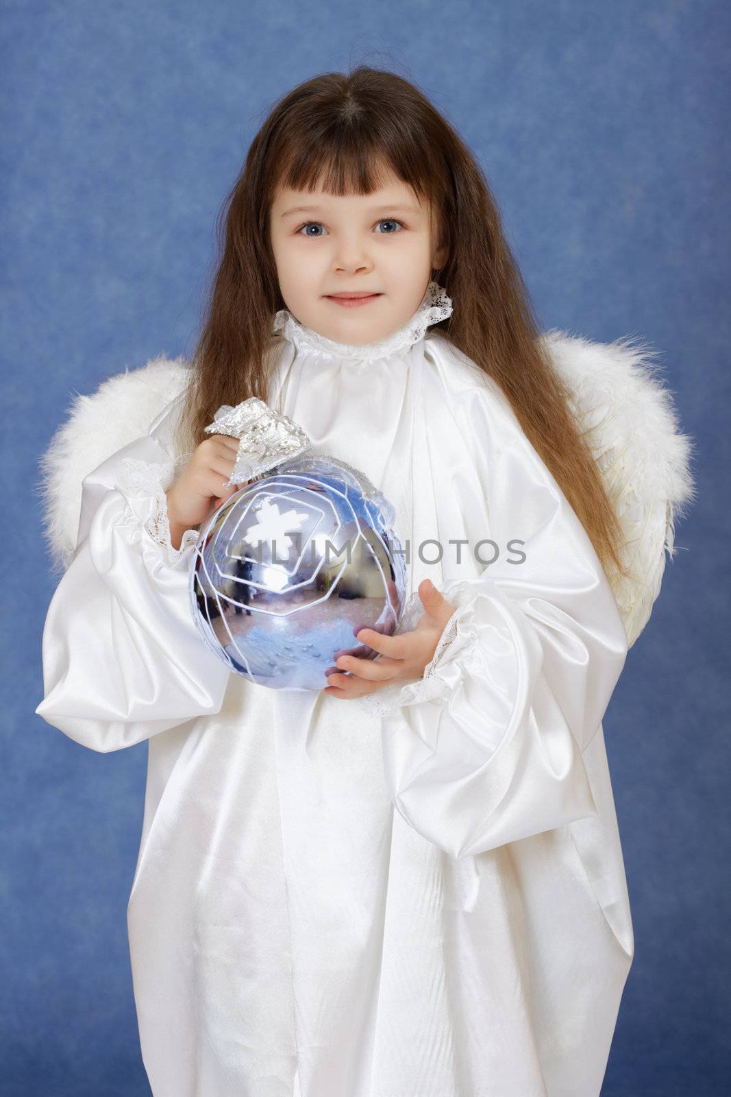 A child dressed as an angel with wings holding a glass ball on blue background