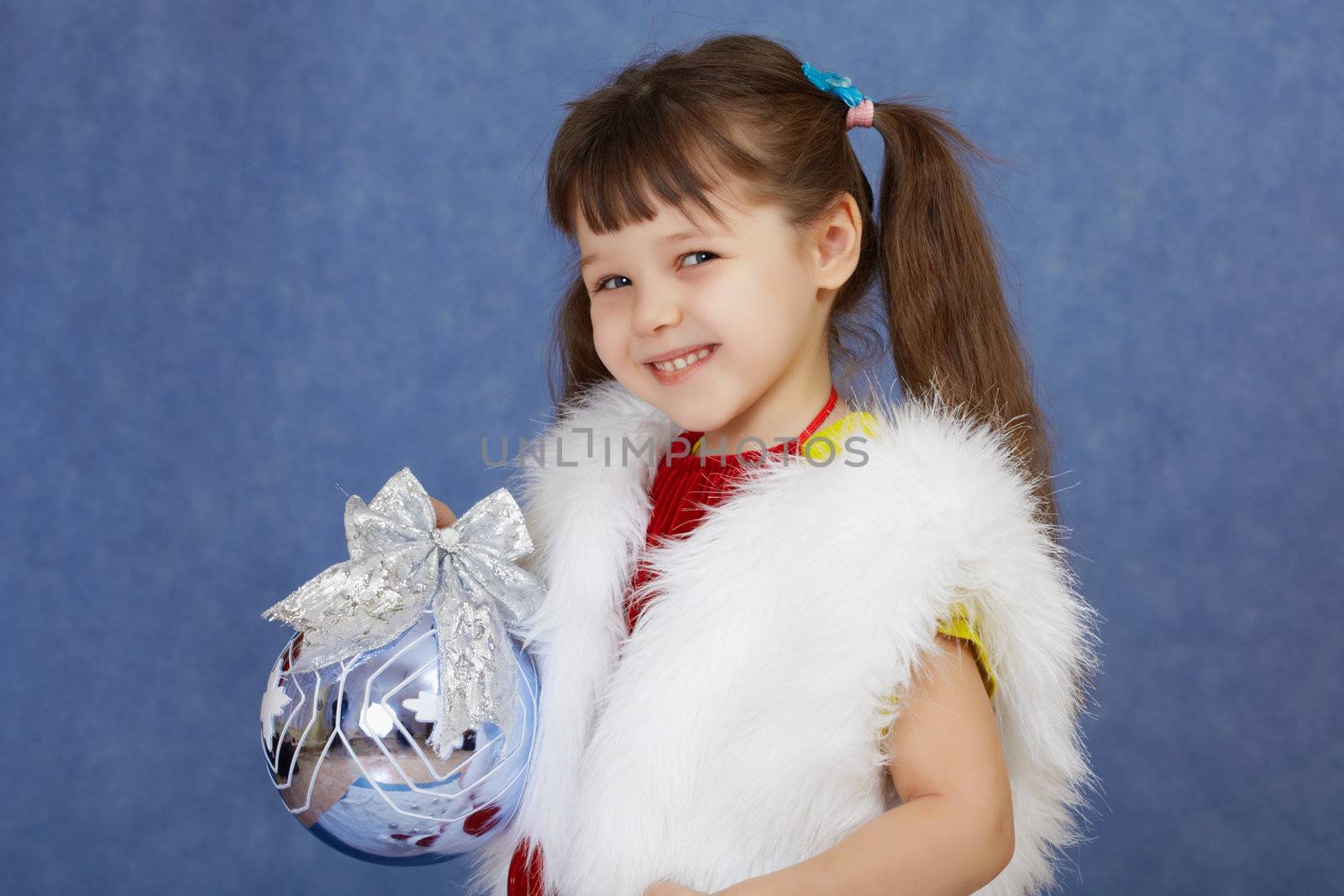 The little girl in a white fur costume holding a glass ball on blue