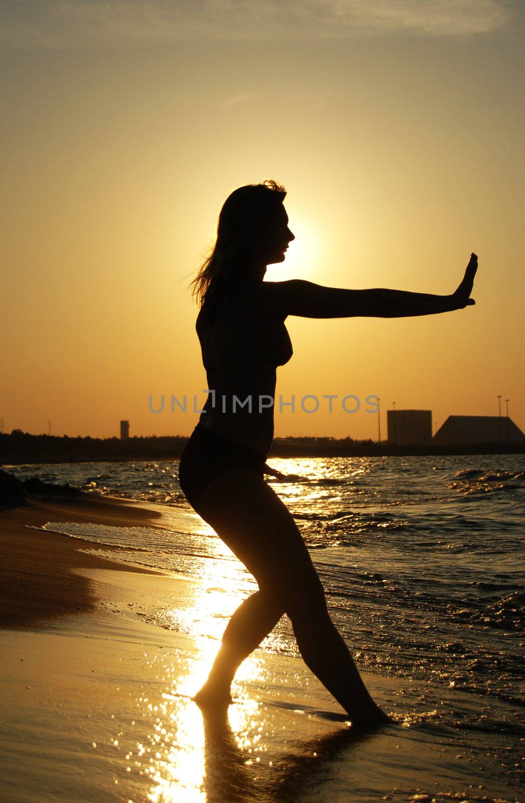 Beautiful girl practising Tai Chi on a beach.