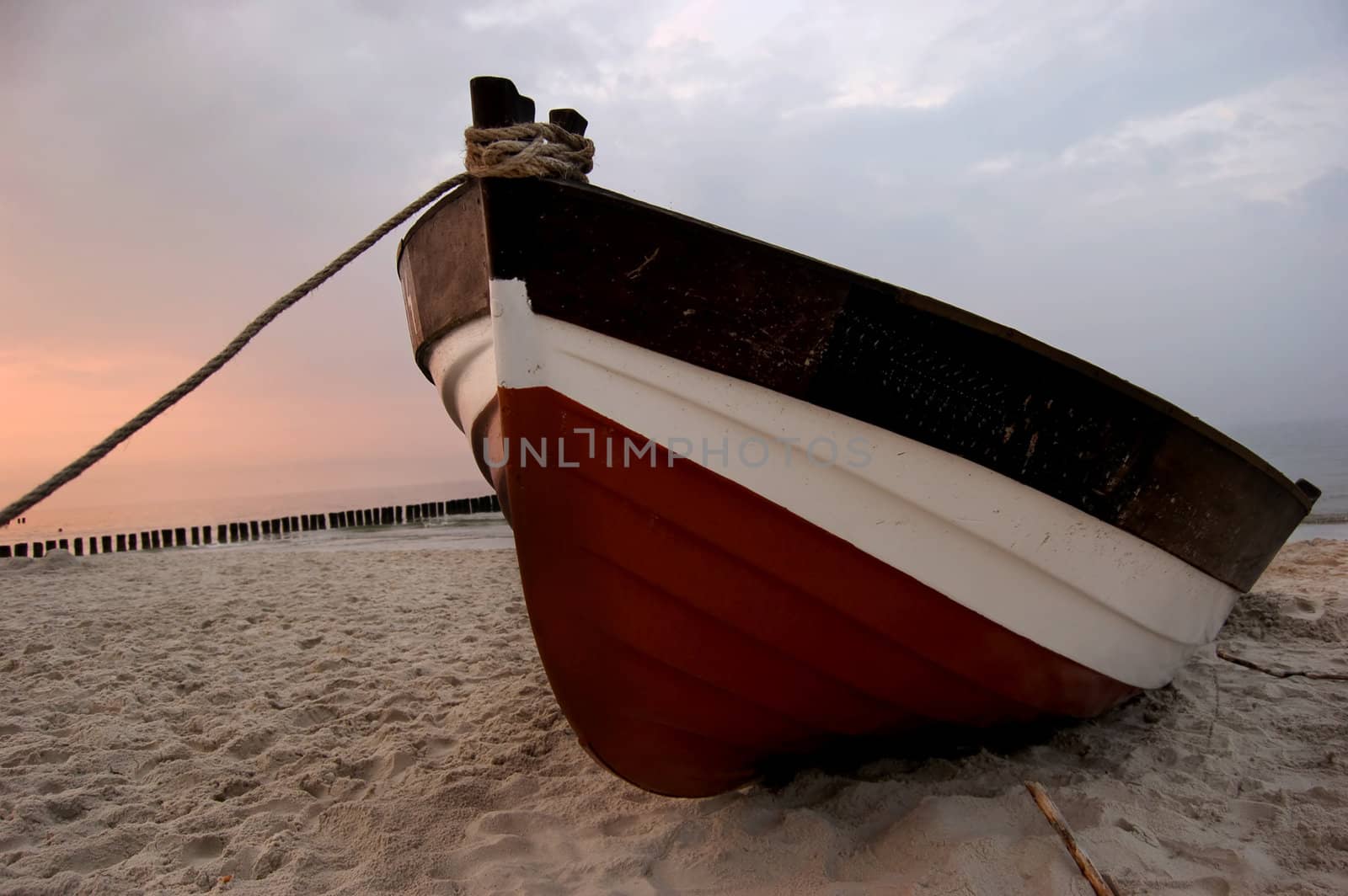 Old fishboat on sandy beach. Beautiful sunset - Baltic Sea in Poland
