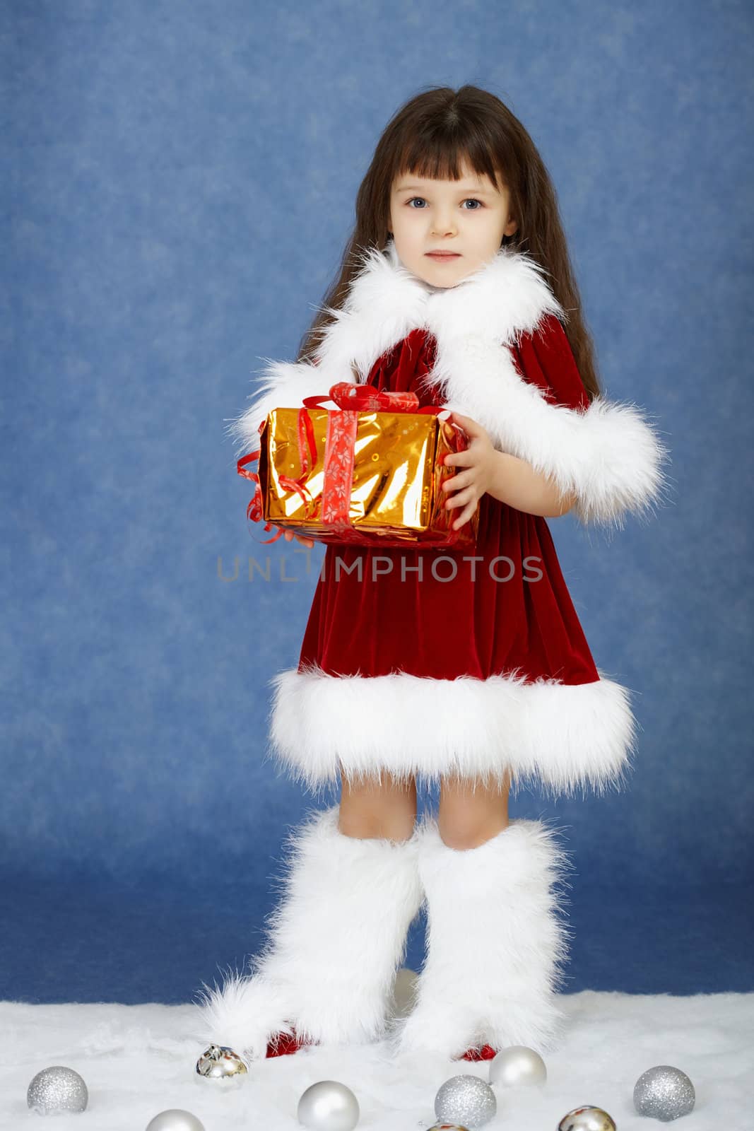 The little girl in fur New Year's clothes with a gift in hands