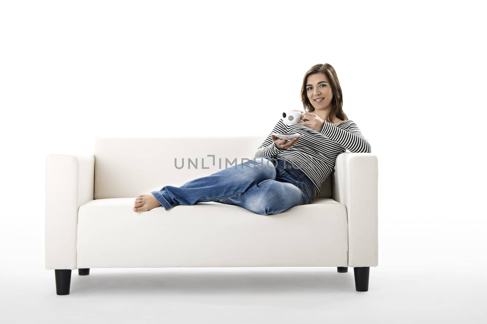 Beautiful woman relaxing on a white sofa with a cup of coffee