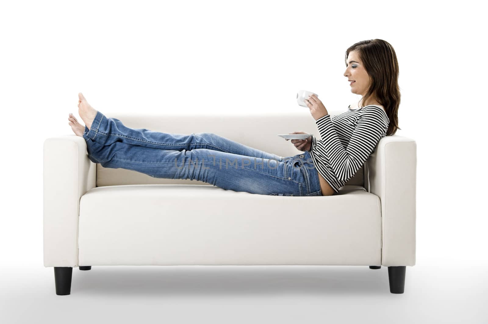 Beautiful woman relaxing on a white sofa with a cup of coffee