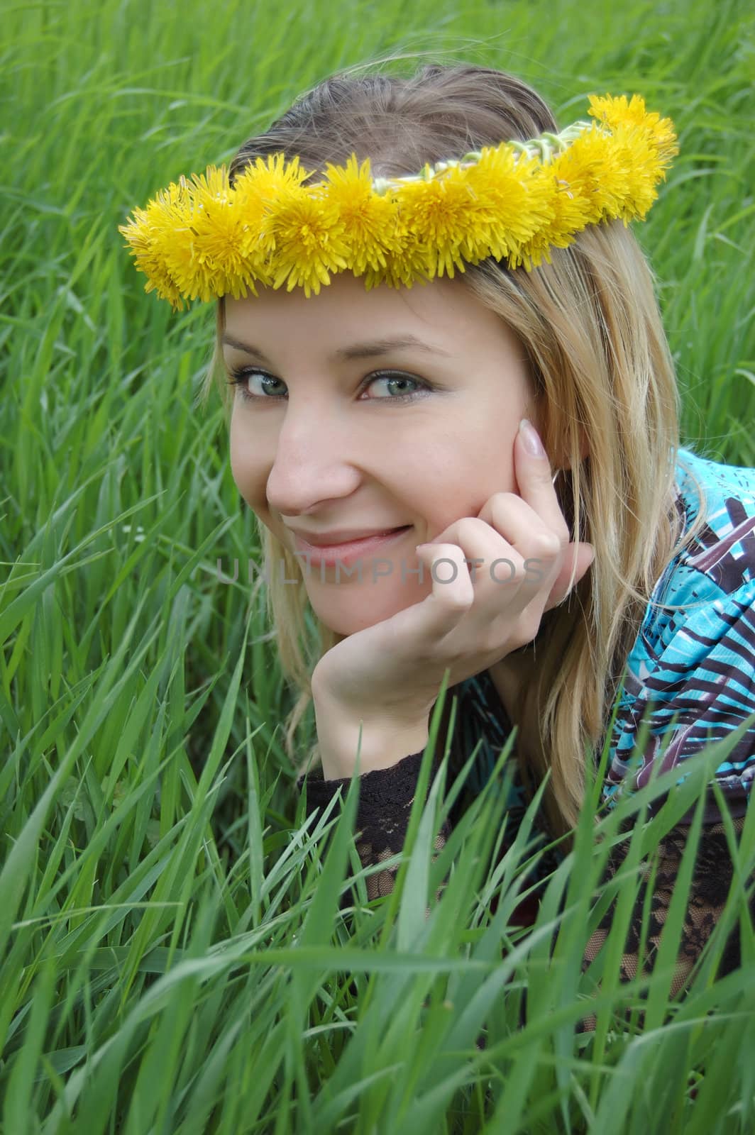 Girl with dandelion diadem over green grass
