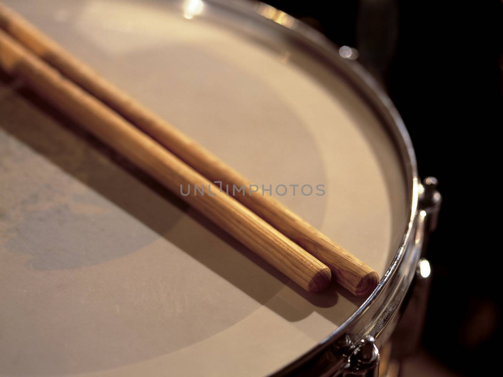 Drumsticks resting on a snare drum between sets of a live show.