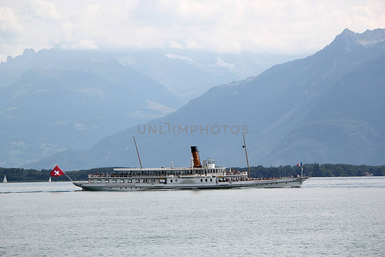 Famous very old steamboat with tourists on the lake of Geneva in front of mountains, Switzerland