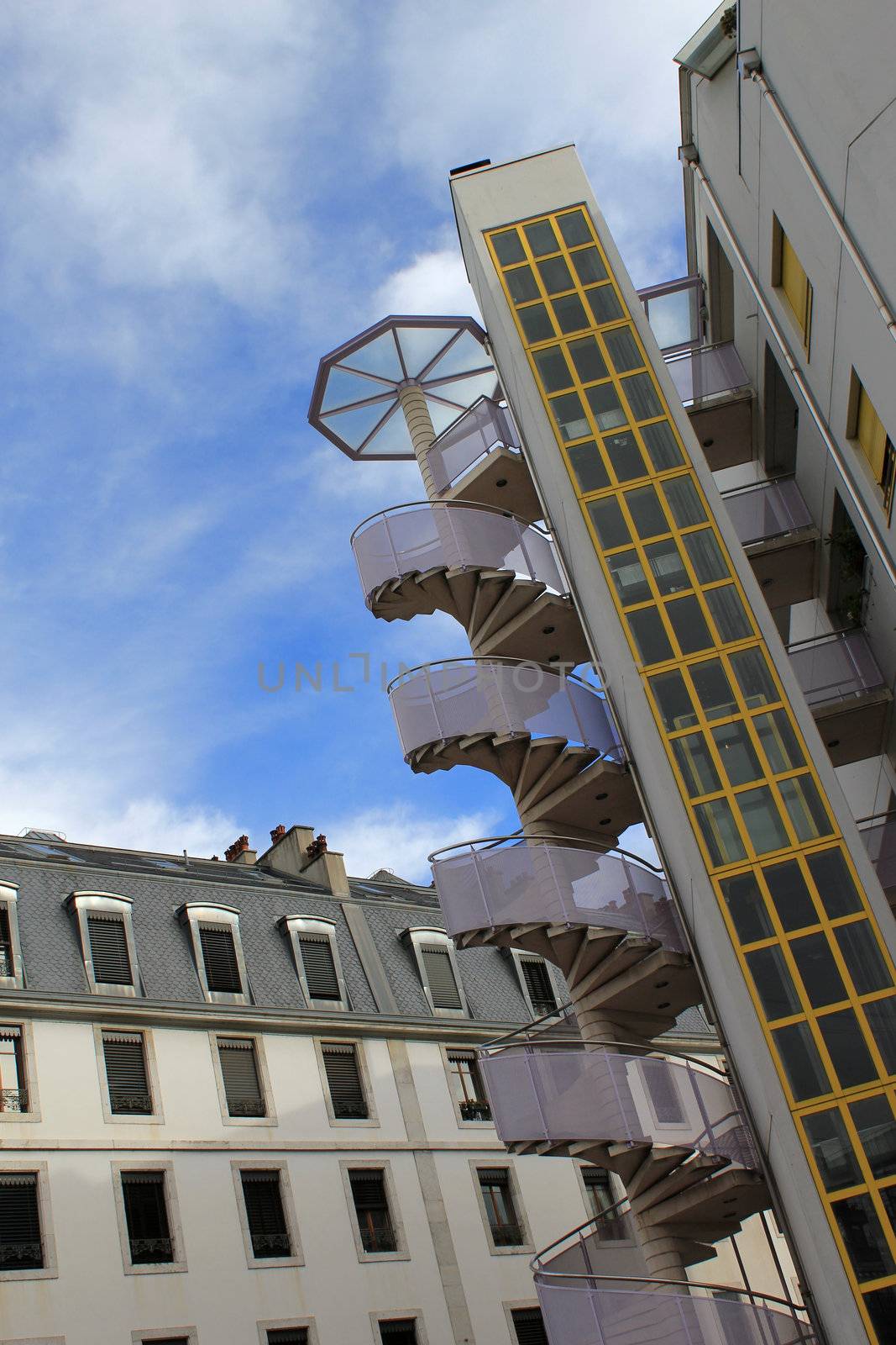 Design outside spiral staircase aside a modern building next to another old one
