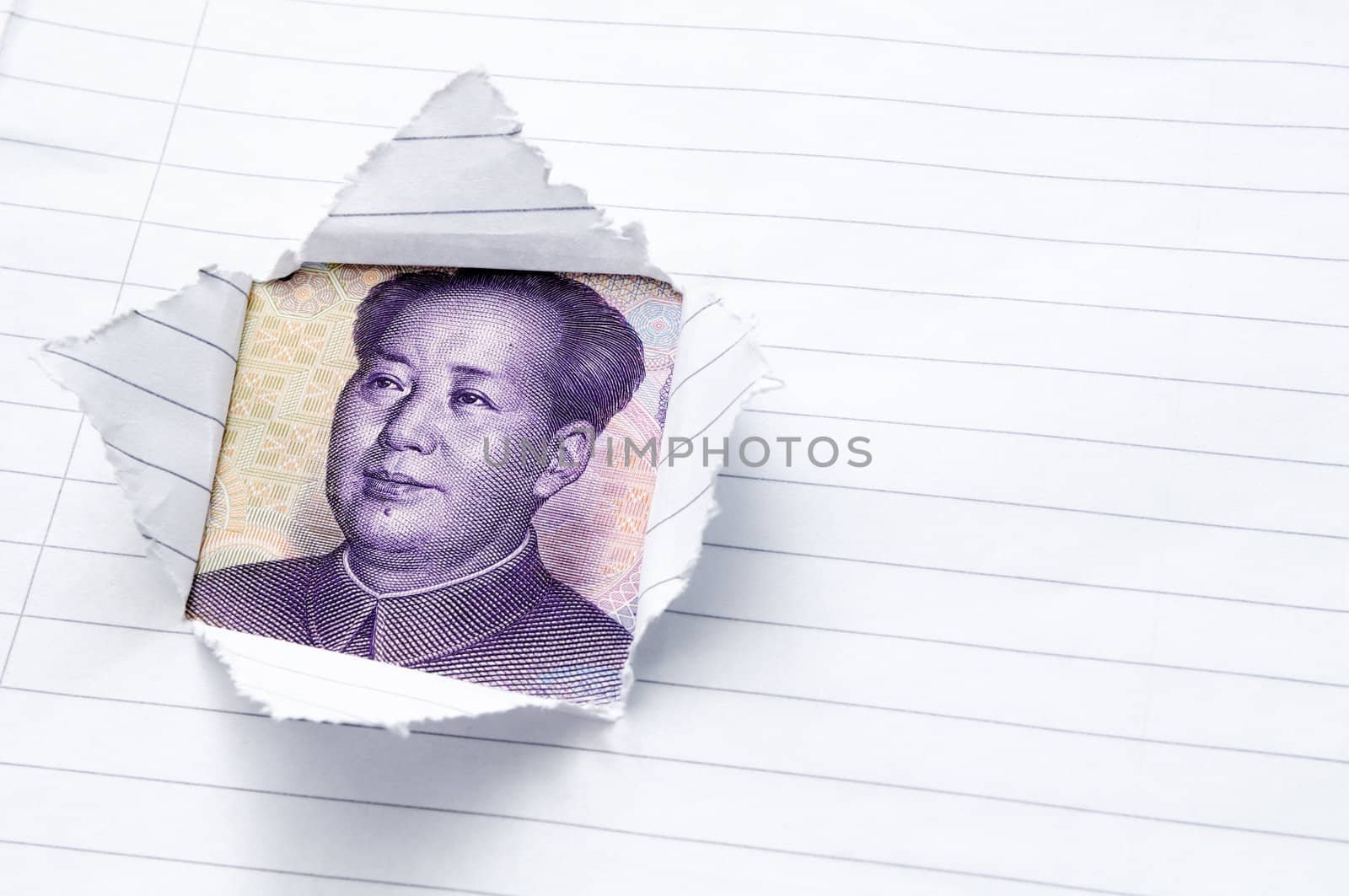 Lined paper torn with window opening showing Chinese currency, the Yuan.
