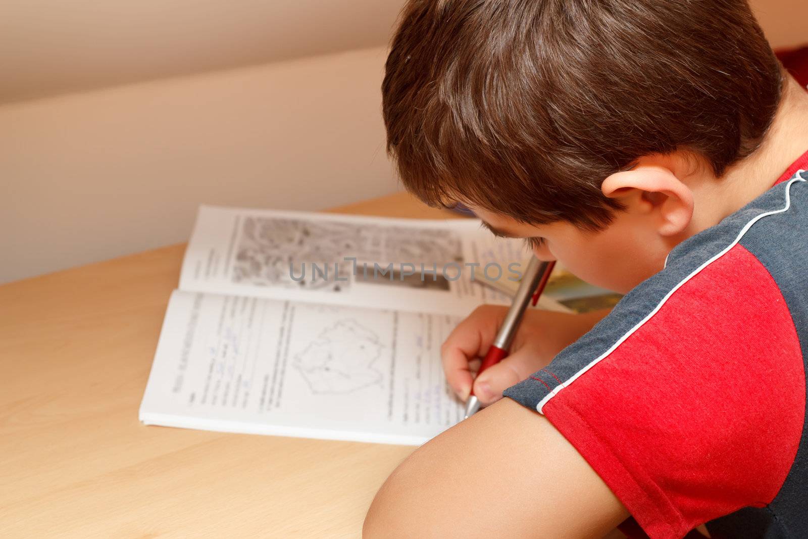 boy doing homework, writing text from workbook