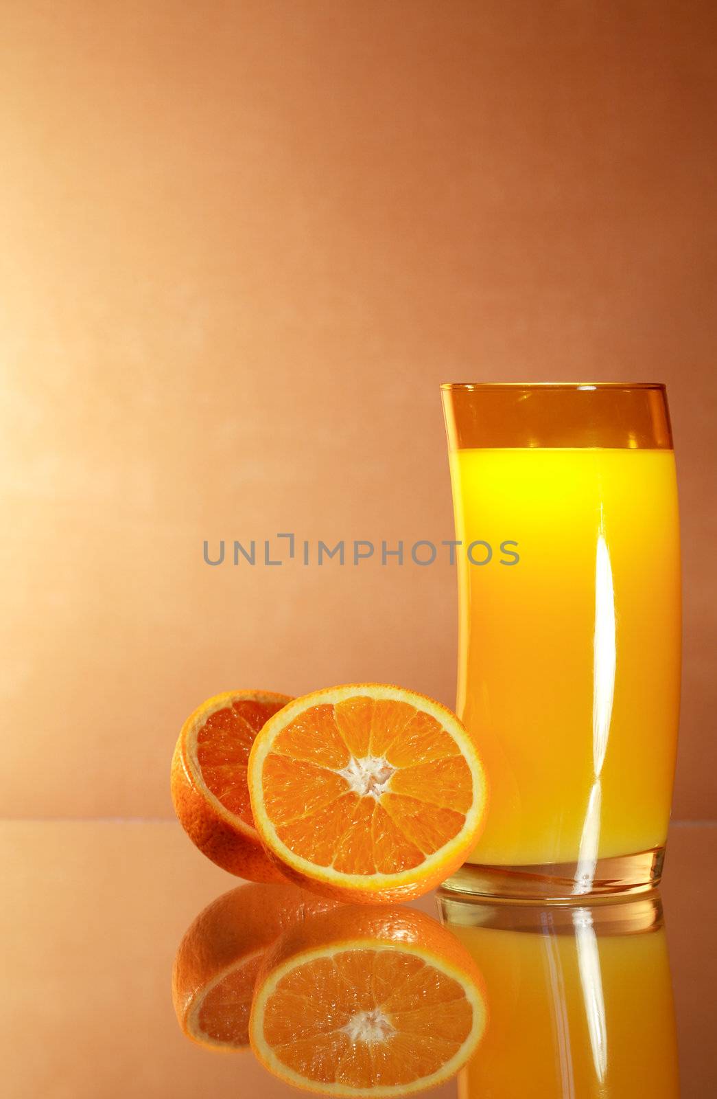 Sliced oranges near glass of orange juice on gradient background with reverberation