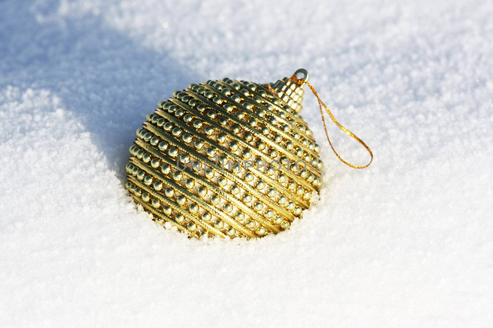 golden christmas bauble in snow by photochecker