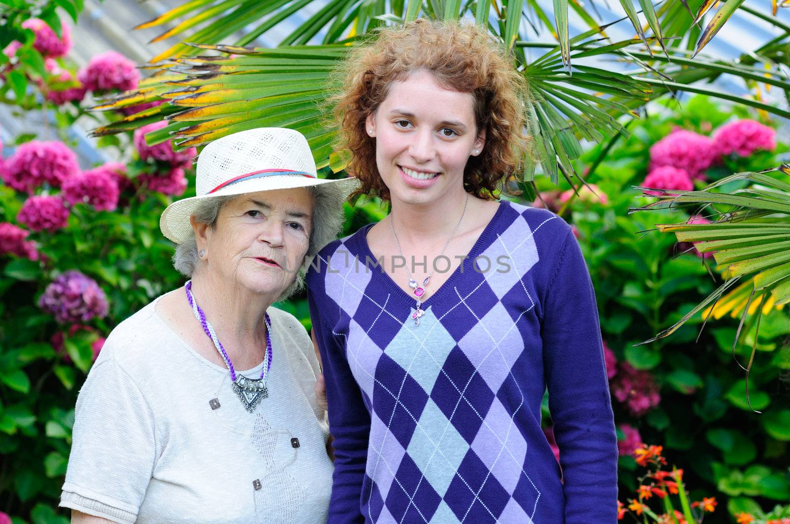 Very old senior woman and young woman smiling in garden